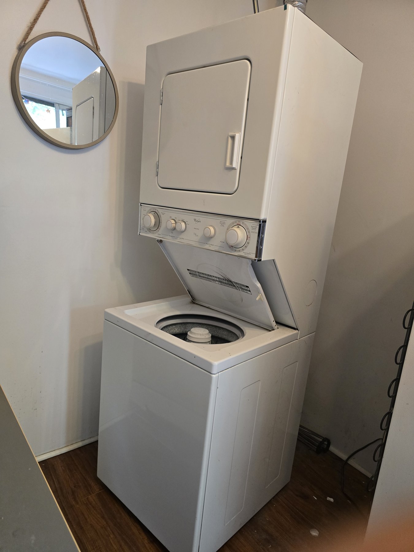 White Whirlpool laundry centre with an upper dryer and open top-load washer